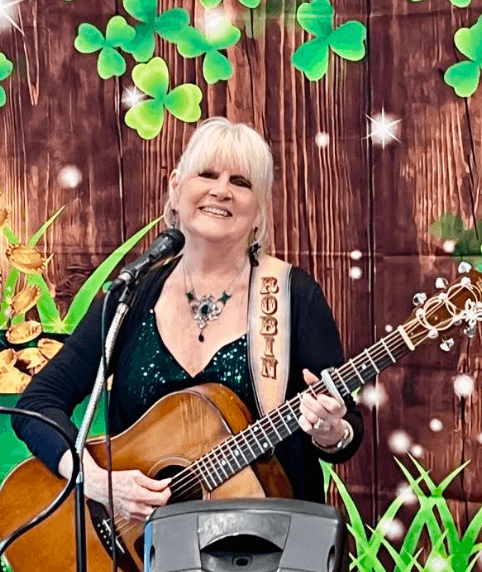 A senior woman playing guitar at a community performance